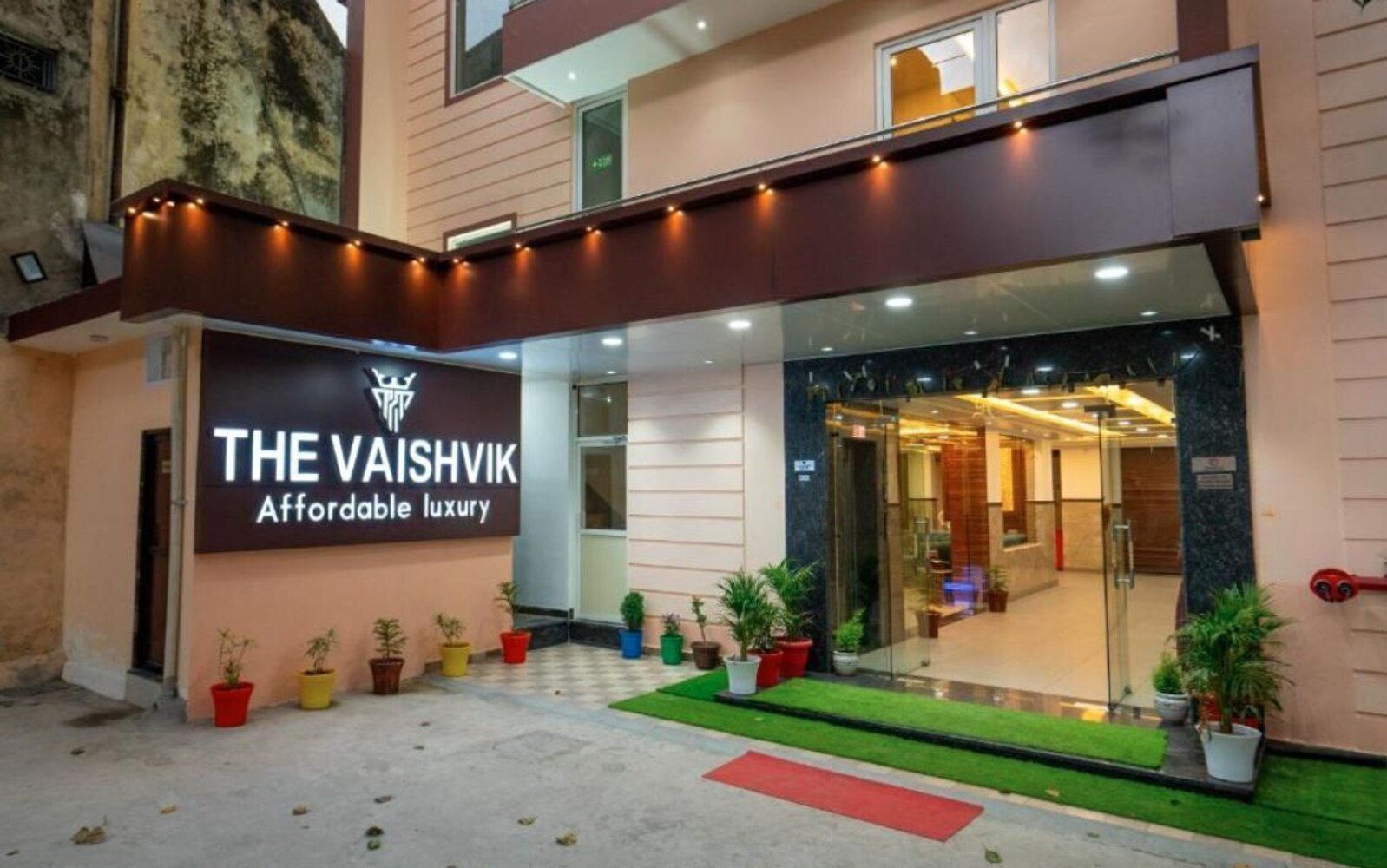 The illuminated entrance of Hotel The Vaishvik